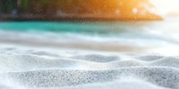 Fresh snow surface with smooth drifts and sparkles in morning sunlight against blurred winter landscape background, natural seasonal outdoor scene.