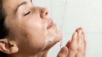 Adult male with medium skin tone washing face with water stream, eyes closed, hands cupping water, skincare and hygiene routine for personal care and wellness content.