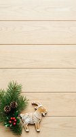 Gingerbread goat cookie with evergreen branches, pinecones and red berries on light wood surface for holiday baking and festive seasonal decorations.