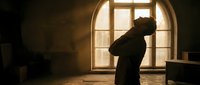 Silhouette of depressed person sitting by window in dark room with warm sunlight streaming through, mental health concept for therapy and wellness designs.