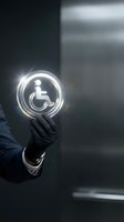 Businessman in dark suit holding glowing neon wheelchair accessibility icon symbol, representing inclusive business practices and disability support services.