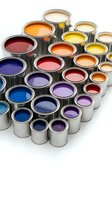 Colorful paint cans with vibrant liquid paints in metal containers arranged on white background for home renovation and interior design projects.