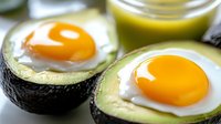 Baked eggs in avocado halves, healthy breakfast with bright yellow yolks and green avocado flesh in close-up view.
