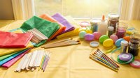 Colorful art supplies arranged on wooden windowsill including paper, paintbrushes, paints and craft materials for creative projects and artistic activities.