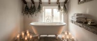 Luxurious spa bathroom with freestanding bathtub, candles, eucalyptus plants and rustic wooden beams creating serene wellness retreat atmosphere.