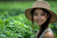 Young Asian woman wearing straw hat smiling in green vegetable garden, long dark hair in braid, casual summer outfit, fresh organic farming concept.