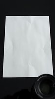 White crumpled paper sheet on black background with magnifying glass corner for business documents, contracts, and office presentations.