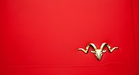Golden decorative ornament with curved horns on vibrant red background, isolated and ready for design projects, invitations, and festive branding applications.