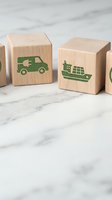 Wooden blocks with green eco-friendly transport icons including electric van and cargo ship on marble surface for sustainable logistics concepts.
