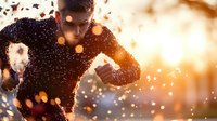 Athletic young Caucasian male runner silhouetted against golden sunset with bokeh light effects and motion blur, creating dramatic sports atmosphere during training.