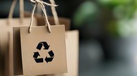 Eco-friendly brown paper shopping bags with recycling symbol and rope handles for sustainable retail packaging and environmental commerce.