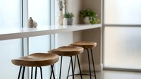 Modern bar stools with wooden seats and black metal legs positioned at a minimalist counter near bright windows, ideal for kitchen and interior design projects.