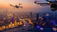 Drones flying over illuminated city skyline at sunset with river and urban lights creating futuristic aerial photography scene for technology concepts.