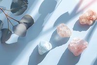 Healing crystals and eucalyptus leaves arranged on white surface with natural shadows for wellness meditation and spiritual energy practices.
