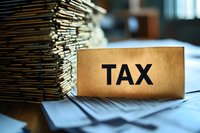 Large stack of tax documents and paperwork with TAX label on desk for accounting and financial planning during tax season preparation.