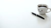 Minimalist workspace with steaming coffee cup featuring cute smiley face and black pen on clean white surface for productivity and morning routine concepts.
