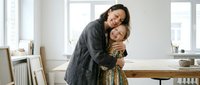 Happy mother and daughter embracing in bright modern kitchen, showing love and family bonding during morning routine at home.
