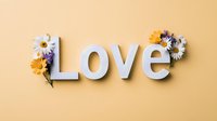 White letters spelling love decorated with fresh daisies and yellow flowers on pastel peach background, creating romantic minimalist composition for valentines cards.