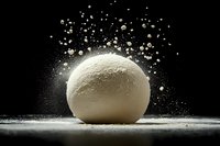 Fresh dough ball with flour explosion against black background, capturing dynamic baking moment for culinary content.