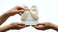 Hands holding white gift box with cream ribbon bow on isolated background, suitable for holiday, celebration, and present giving concepts.