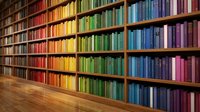 Colorful library bookshelf with rainbow arrangement of books from red to purple creating vibrant literary collection for education and reading concepts.