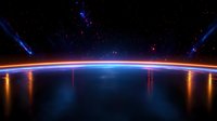 Glowing horizon of Earth from space with vibrant blue and orange light streaks, stars and cosmic rays against dark universe background.