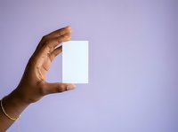 Hand holding blank white card against purple background, suitable for product mockups, branding presentations, and business marketing materials.