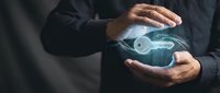 Businessman in dark suit holding glowing electric car hologram between hands, representing sustainable transportation technology and future mobility innovation.
