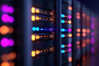 Network server rack with glowing LED indicators in orange, purple and blue colors creating bokeh effect in dark data center environment.