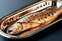 Grilled whole trout with crispy skin served on elongated silver platter against dark background, fresh seafood preparation showing golden-brown sear marks.