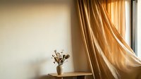Dried flowers in ceramic vase on wooden table with golden curtains and sunlight streaming through window, suitable for home decor and interior design projects.