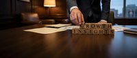 Professional businessman arranging wooden letter blocks spelling GROWTH INSIGHTS on office desk during strategic planning meeting in corporate boardroom.