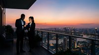 Young couple in formal business attire toasting with champagne glasses on high-rise balcony at sunset, cityscape backdrop, celebration and success concept for corporate events.