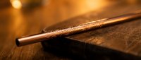 Vintage leather-bound book with antique brass pen on wooden surface in warm candlelight creating nostalgic writing atmosphere for literary projects.