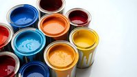 Colorful paint cans with vibrant liquid paint in blue, red, orange, yellow and other bright colors for home renovation and creative projects.