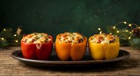 Colorful stuffed bell peppers filled with rice and herbs on rustic wooden table with festive holiday lights creating warm cozy atmosphere for dinner celebration.