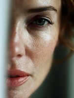 Close up portrait of young Caucasian woman's face showing natural skin texture, freckles, green eye and coral lips in soft natural lighting.
