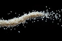 Flying white rice grains scattered in dynamic motion against black background, creating elegant curve pattern for food and culinary design projects.