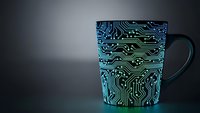 Modern coffee mug with glowing circuit board pattern in blue and green neon colors on dark background for technology and digital lifestyle concepts.