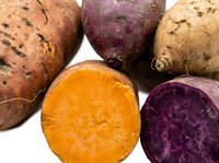 Fresh organic sweet potatoes with vibrant orange and purple flesh displayed on white background for healthy cooking and nutrition concepts.