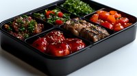 Asian bento box lunch with grilled meat, sweet and sour chicken, fresh vegetables and herbs in black container on white background, food delivery concept.