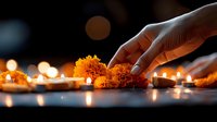 Hand arranging orange marigold flowers and lit candles in spiritual ceremony setting with soft bokeh lights creating peaceful atmospheric ambiance.
