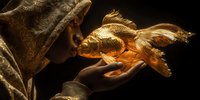 Golden fish sculpture emerging from ornate treasure chest with flowing fins and detailed scales against dark background for luxury decor concepts.
