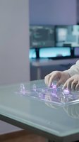 Hands interacting with holographic network interface on glass table in modern office environment with digital connectivity visualization.