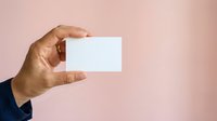 Male hand holding blank white business card against pink background, suitable for branding, corporate identity, and marketing mockup designs.