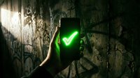 Hand holding smartphone displaying glowing green checkmark on cracked concrete wall. Success, approval, and confirmation concept for business, technology, and digital validation projects.