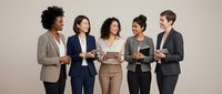 Diverse group of five professional women standing together holding digital tablets and documents against neutral background for corporate teamwork concepts.
