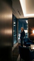 Professional businesswoman in luxury office suite overlooking city skyline at night. Corporate executive contemplating urban landscape from modern workspace.
