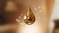 Golden oil drop with floating bubbles on warm blurred background for skincare and cosmetic product advertising.