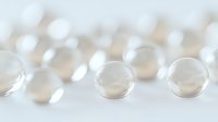 Translucent glass spheres arranged in rows creating minimalist composition with soft bokeh effect and white background, suitable for abstract design projects.